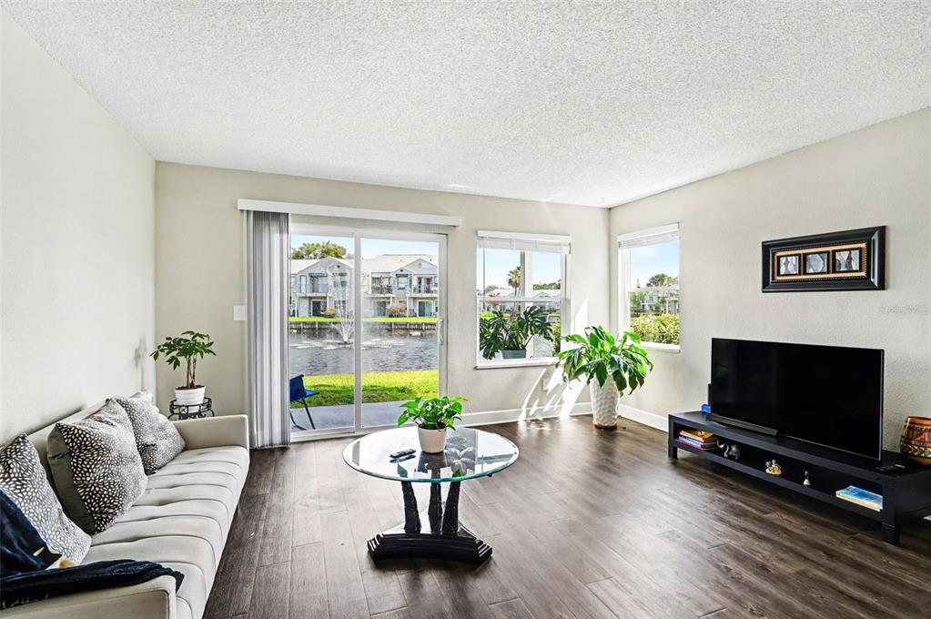 A living room features dark wood flooring, a glass coffee table, and a sliding glass door — 2552 WOODGATE BOULEVARD UNIT 107, ORLANDO, FL
