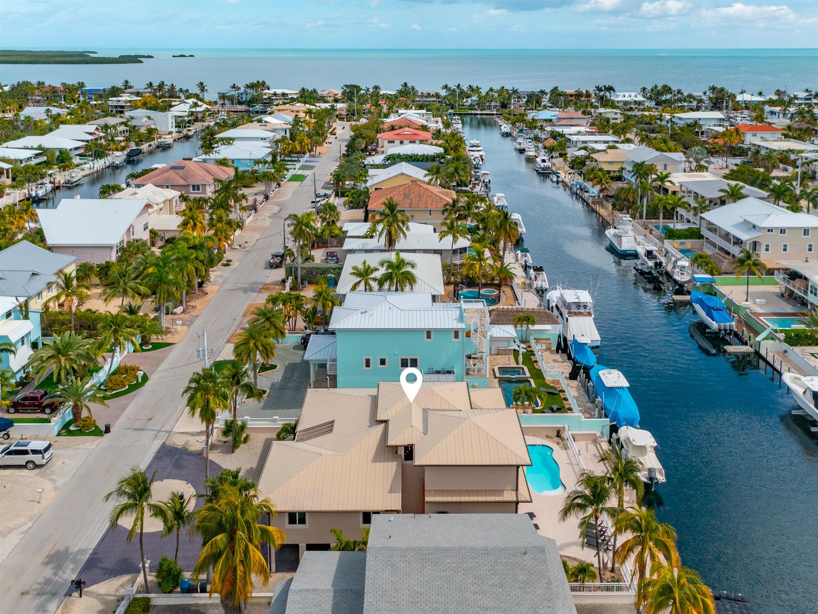 An aerial view shows a tan house with a pool along a canal — 397 Laguna Avenue, Key Largo FL 33037, KEY LARGO, FL