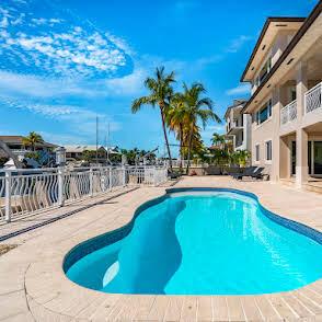 A swimming pool sits on a patio next to a multi-story building by a canal — 397 Laguna Avenue, Key Largo FL 33037, KEY LARGO, FL