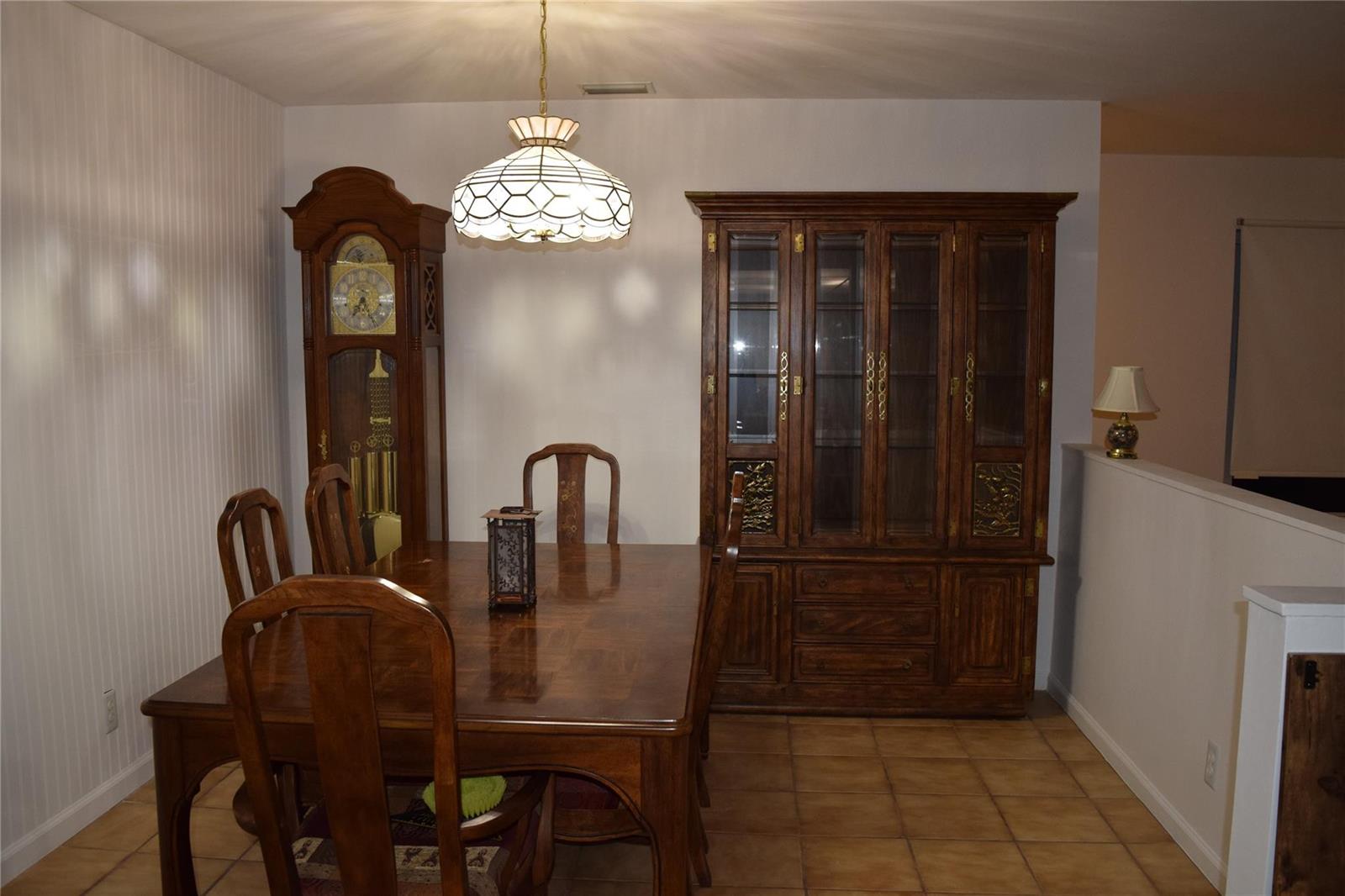 A dining room features a wooden table, chairs, a grandfather clock, and a large china cabinet — 3642 Harlowe Avenue, Boynton Beach FL 33436, BOYNTON BEACH, FL