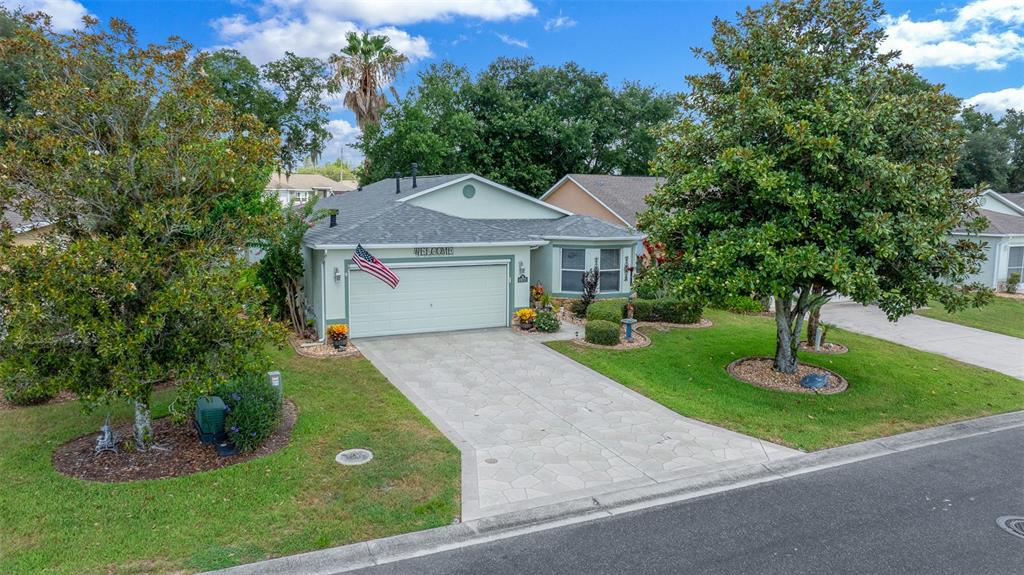 An exterior view of a single-story house with a light green facade and paved driveway — 15771 SW 13TH CIRCLE, OCALA, FL