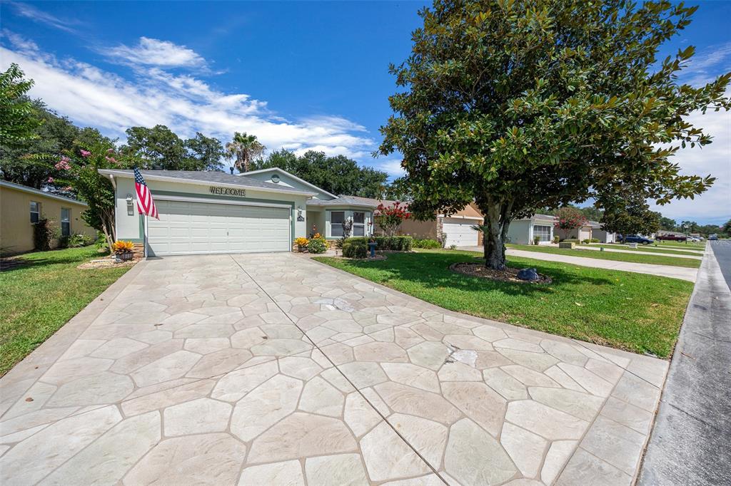 A single-story house with a stone-patterned driveway, a two-car garage, and a large tree — 15771 SW 13TH CIRCLE, OCALA, FL