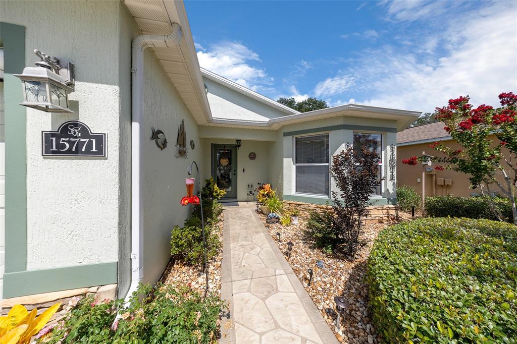 A stone walkway leads to the front entrance of a house with light-colored stucco walls — 15771 SW 13TH CIRCLE, OCALA, FL