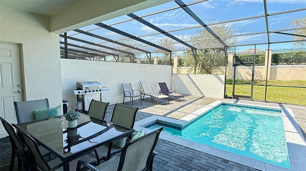 A screened-in patio features a swimming pool, outdoor dining set, and a grill — 2414 DUBAI STREET, KISSIMMEE, FL