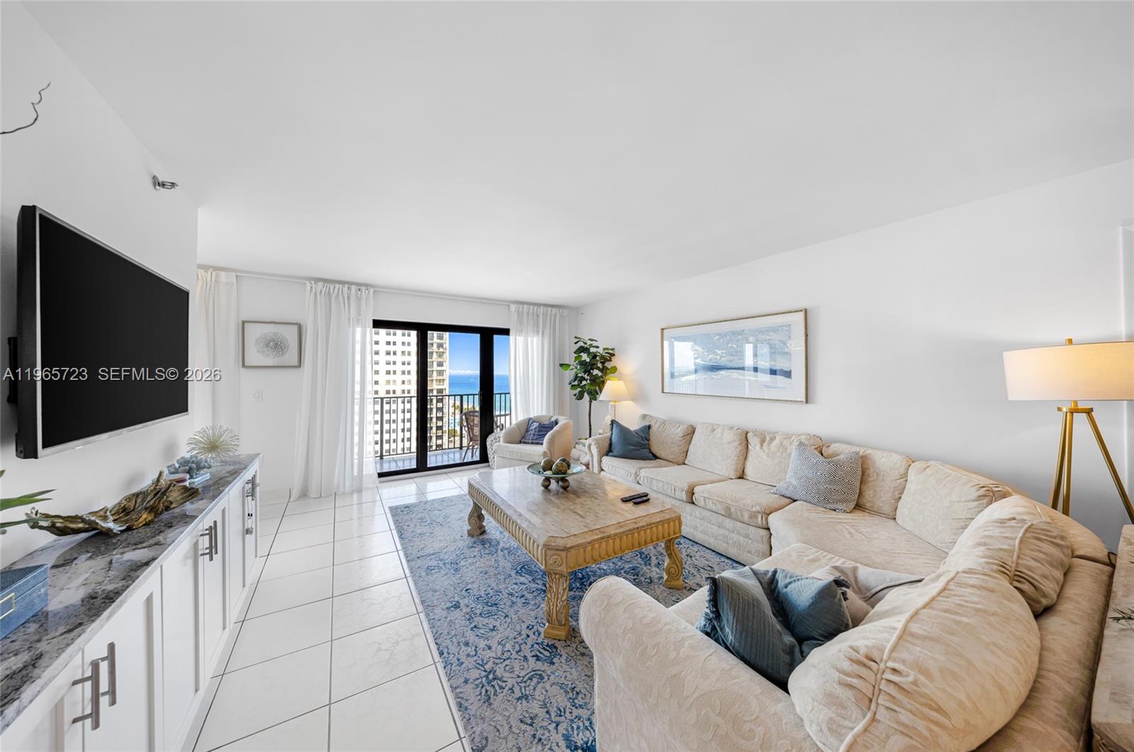 A living room features a sectional sofa, a coffee table, and a balcony with ocean views — 1201 S Ocean Dr # 1903S, Hollywood FL 33019, HOLLYWOOD, FL