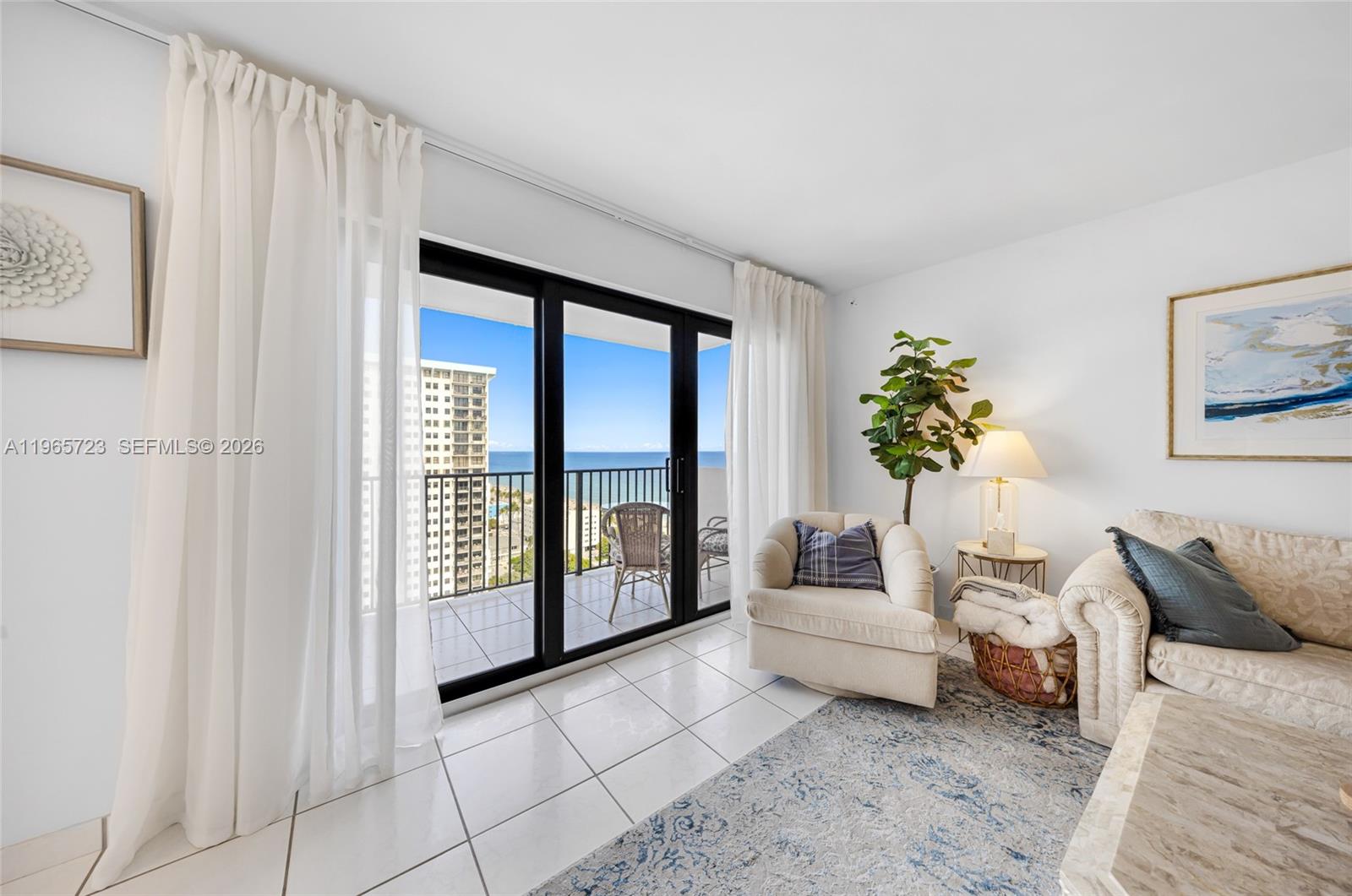 A living room features white tile floors, a sliding glass door, and a balcony view — 1201 S Ocean Dr # 1903S, Hollywood FL 33019, HOLLYWOOD, FL