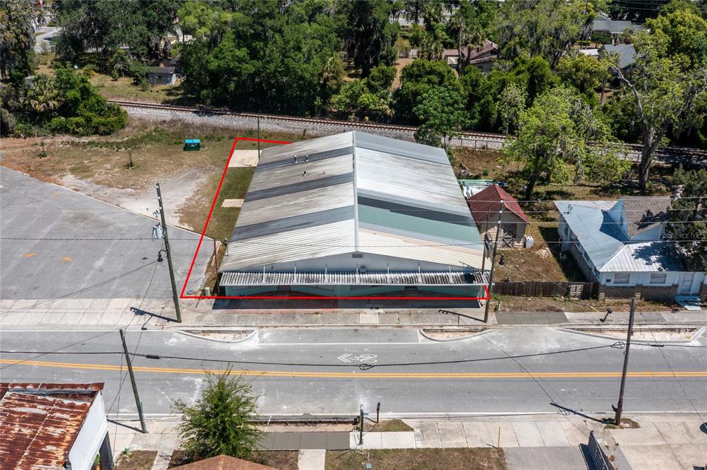 An aerial view shows a commercial building with a metal roof next to railroad tracks — 6945 SE 221ST STREET, HAWTHORNE, FL
