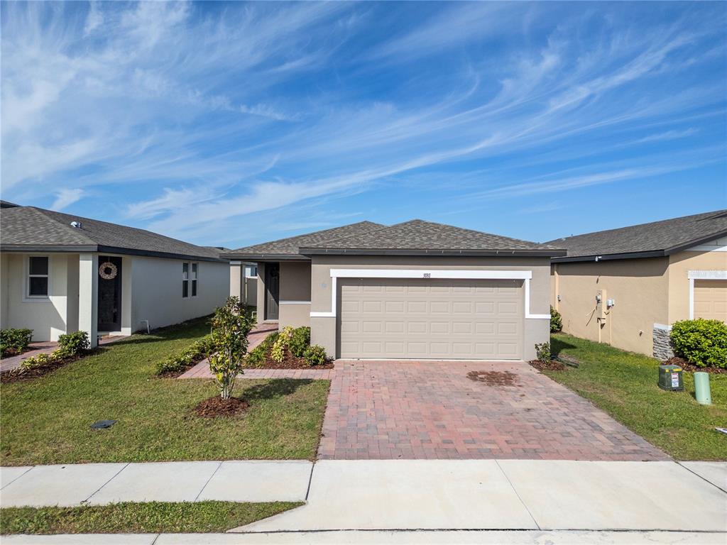 A single-story house features a tan exterior, a two-car garage, and a brick paver driveway — 3181 VICEROY COURT, KISSIMMEE, FL