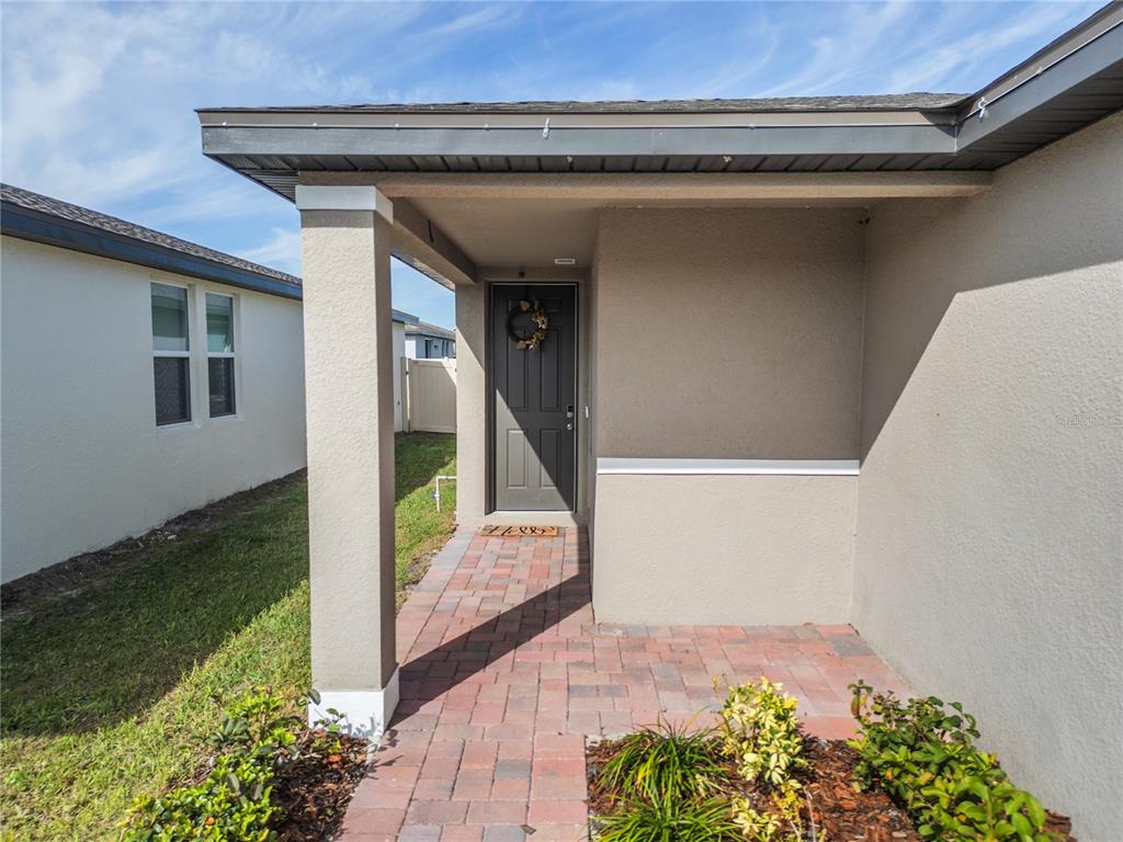A covered entryway features a brick paver walkway leading to a dark gray front door — 3181 VICEROY COURT, KISSIMMEE, FL