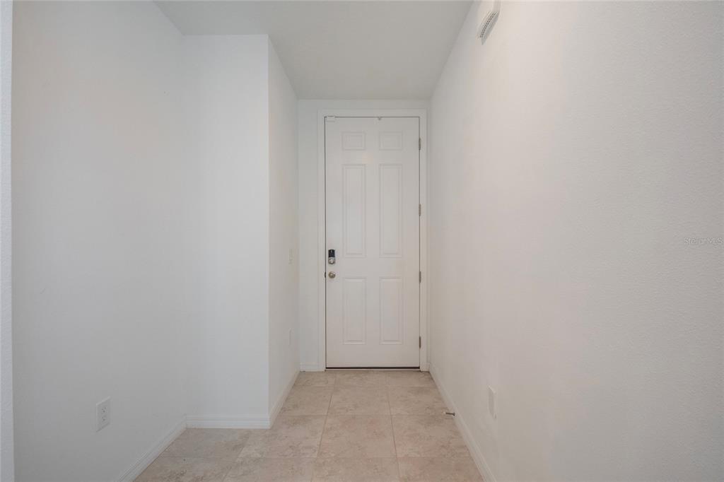 A white door with a smart lock stands at the end of a tiled entryway — 3181 VICEROY COURT, KISSIMMEE, FL