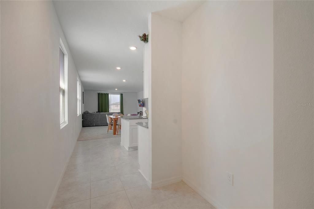 A tiled hallway leads to an open-concept kitchen and living area with light-colored walls — 3181 VICEROY COURT, KISSIMMEE, FL