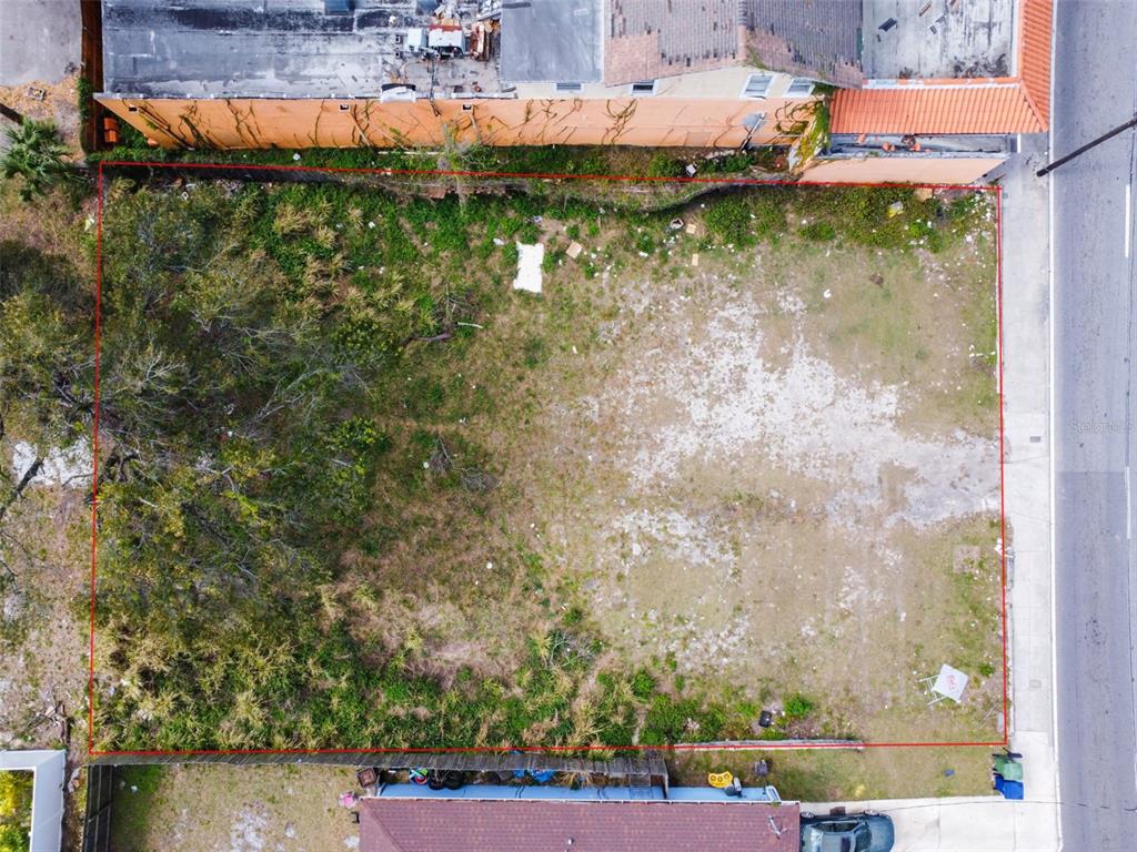 An aerial view shows a rectangular vacant lot bordered by a fence and a building — 2213 E COLUMBUS DRIVE, TAMPA, FL