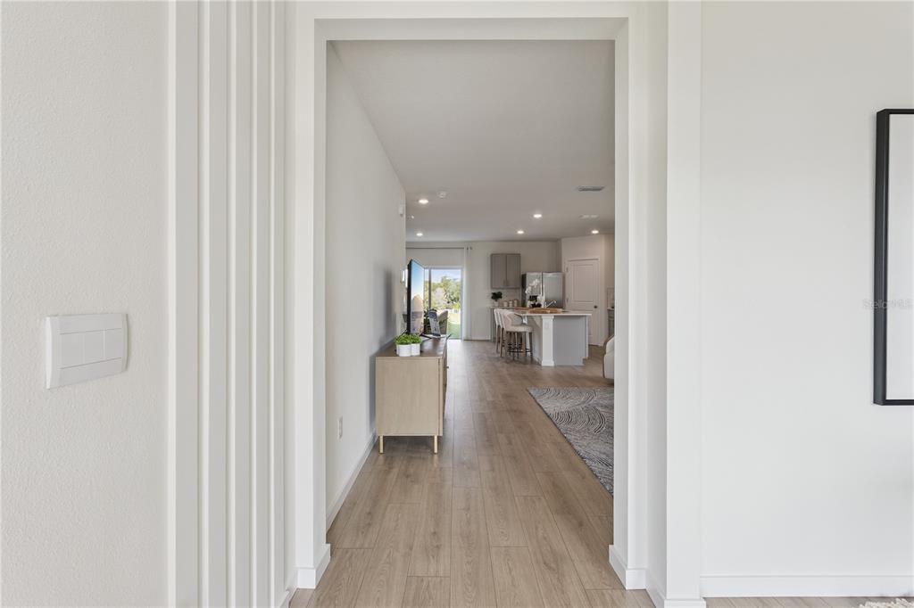 A view through a doorway into a kitchen and living area with wood-look flooring — 5066 MARSHELDER STREET, APOPKA, FL
