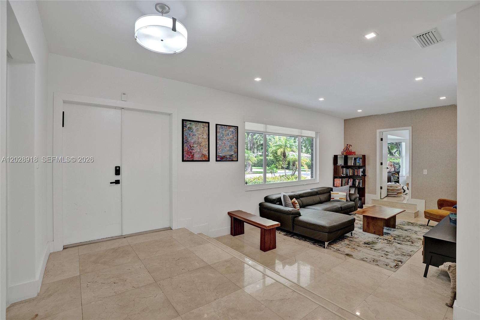 A living room features a dark leather sectional, tile flooring, and a large window — 18641 NE 21st Ave, Miami FL 33179, MIAMI, FL
