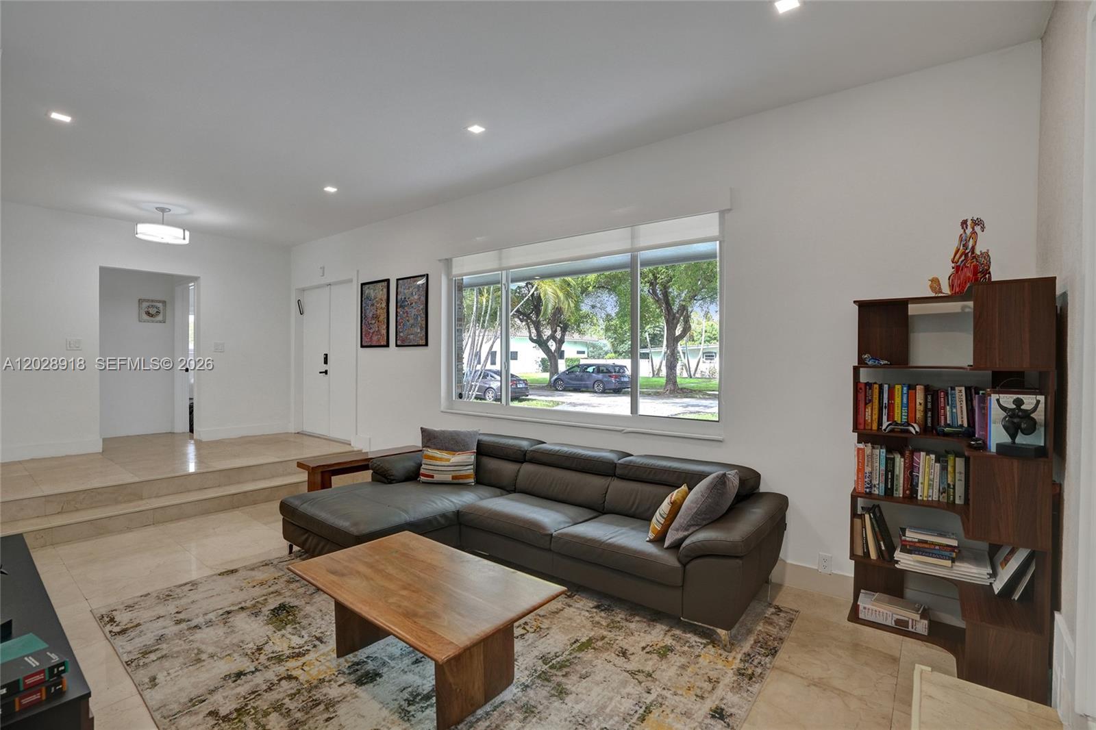 A living room features a dark leather sectional, wooden coffee table, and a bookshelf — 18641 NE 21st Ave, Miami FL 33179, MIAMI, FL