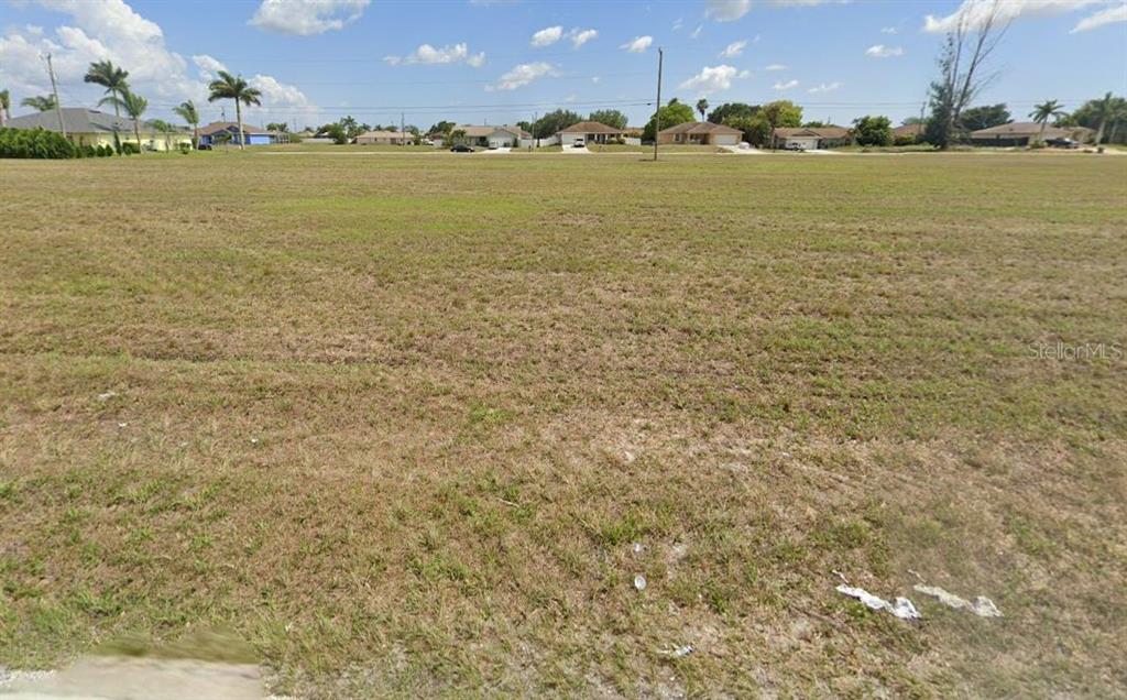 A large, flat, grassy vacant lot sits in front of a residential neighborhood — 2016 DIPLOMAT PARKWAY E, CAPE CORAL, FL