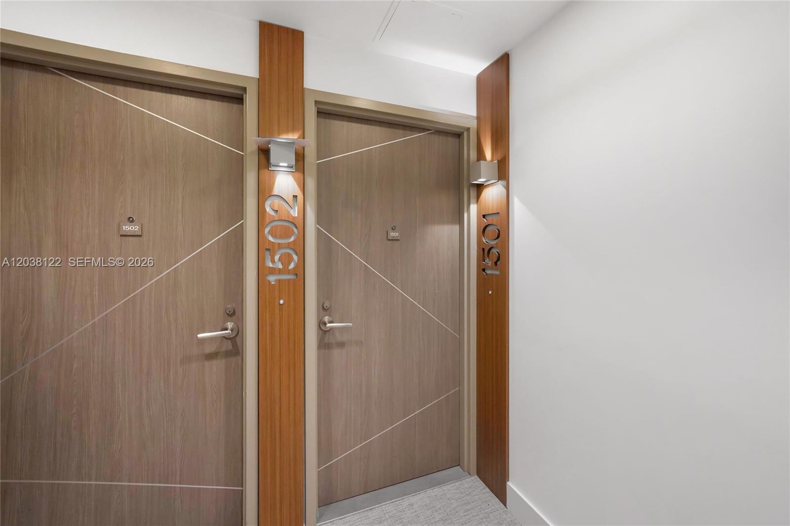 Two apartment doors with wood-grain finish and metal room numbers are set in a hallway — 601 NE 27th St # 1501, Miami FL 33137, MIAMI, FL