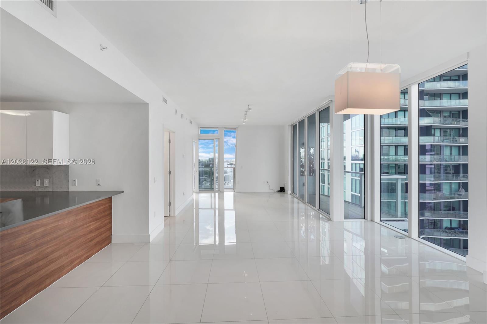 A modern, open-concept living area features white tile floors, a kitchen island, and floor-to-ceiling windows — 601 NE 27th St # 1501, Miami FL 33137, MIAMI, FL