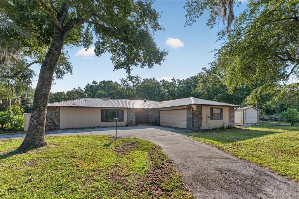 A single-story house with a metal roof, stone accents, and an attached garage — 3385 WOODBERRY COURT, KISSIMMEE, FL