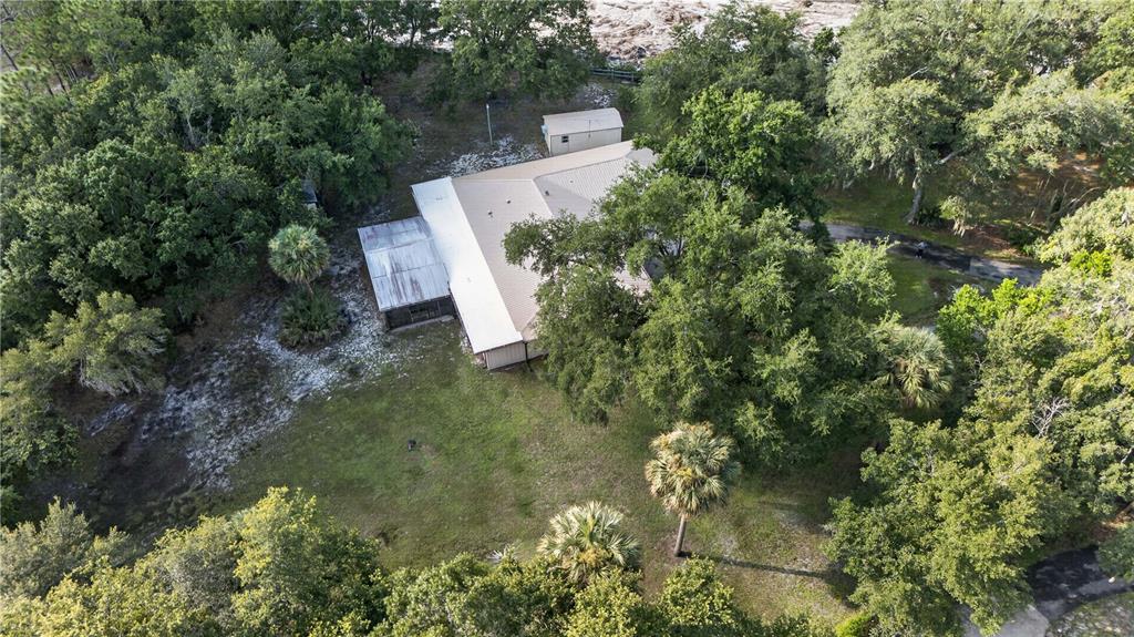 An aerial view shows a house with a metal roof surrounded by trees and grass — 3385 WOODBERRY COURT, KISSIMMEE, FL