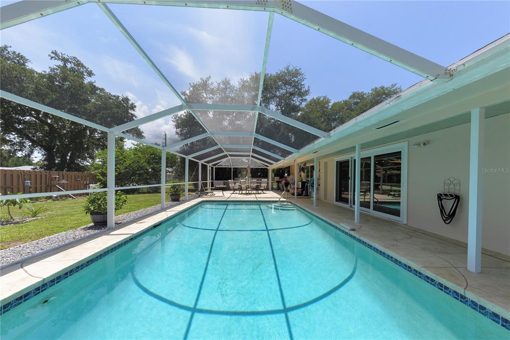 A rectangular swimming pool enclosed by a screened lanai next to a house — 1175 BEAUMONT AVENUE, PORT CHARLOTTE, FL