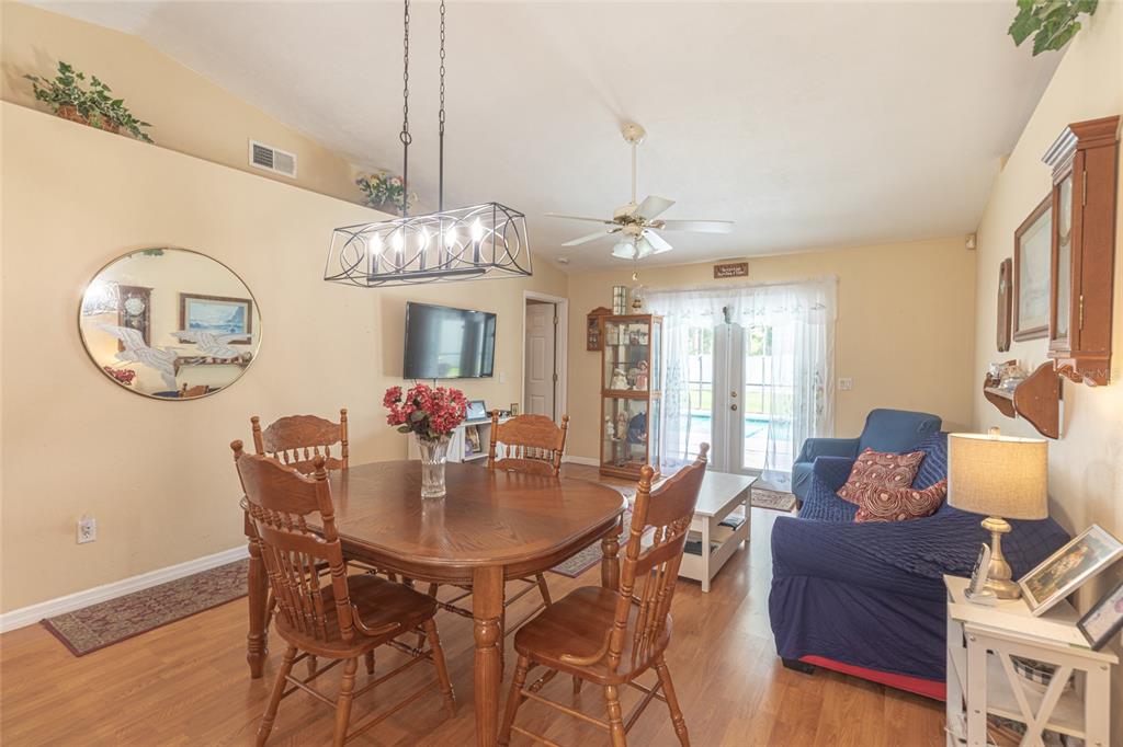 A dining area and living room with wood-look flooring, a wooden table, and blue furniture — 103 EASTWOOD DRIVE, PALM COAST, FL