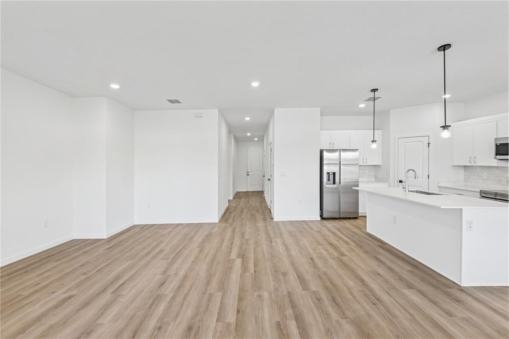 An open-concept kitchen and living area features white cabinetry, stainless steel appliances, and wood-look flooring — 17875 SW 68TH PLACE, DUNNELLON, FL