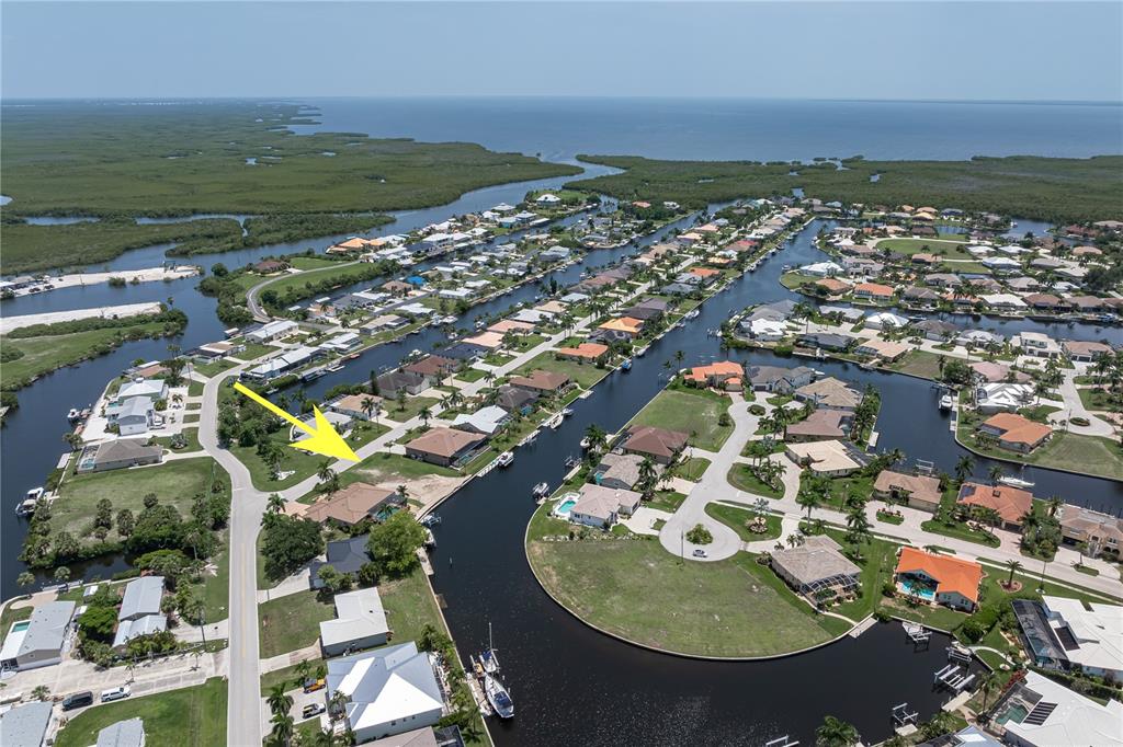 An aerial view shows waterfront homes along canals leading to a large body of water — 5143 ALMAR DRIVE, PUNTA GORDA, FL