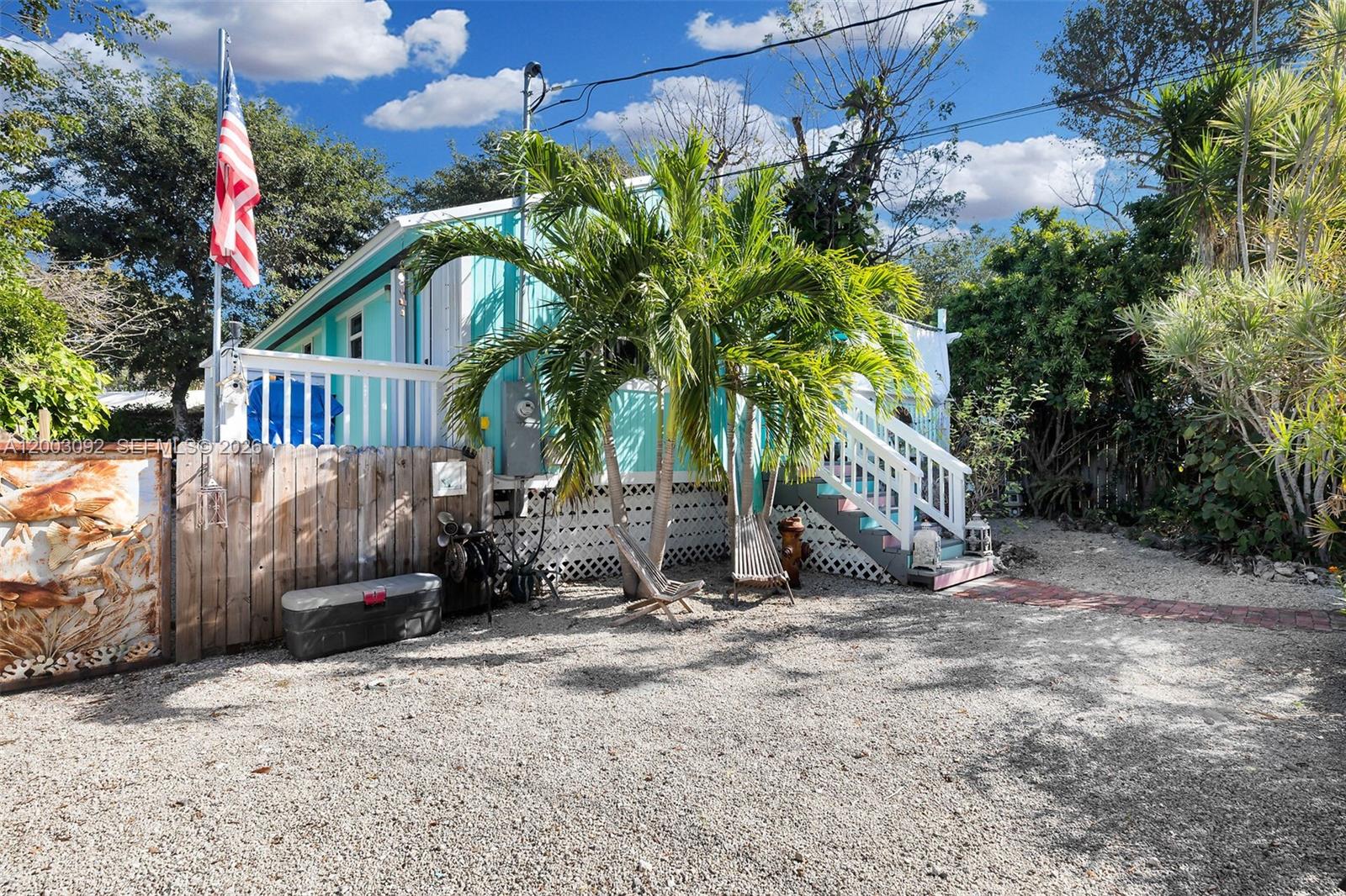 A turquoise house with a white porch and stairs sits behind a gravel driveway — 14 Bonita Ave, Key Largo FL 33037, KEY LARGO, FL