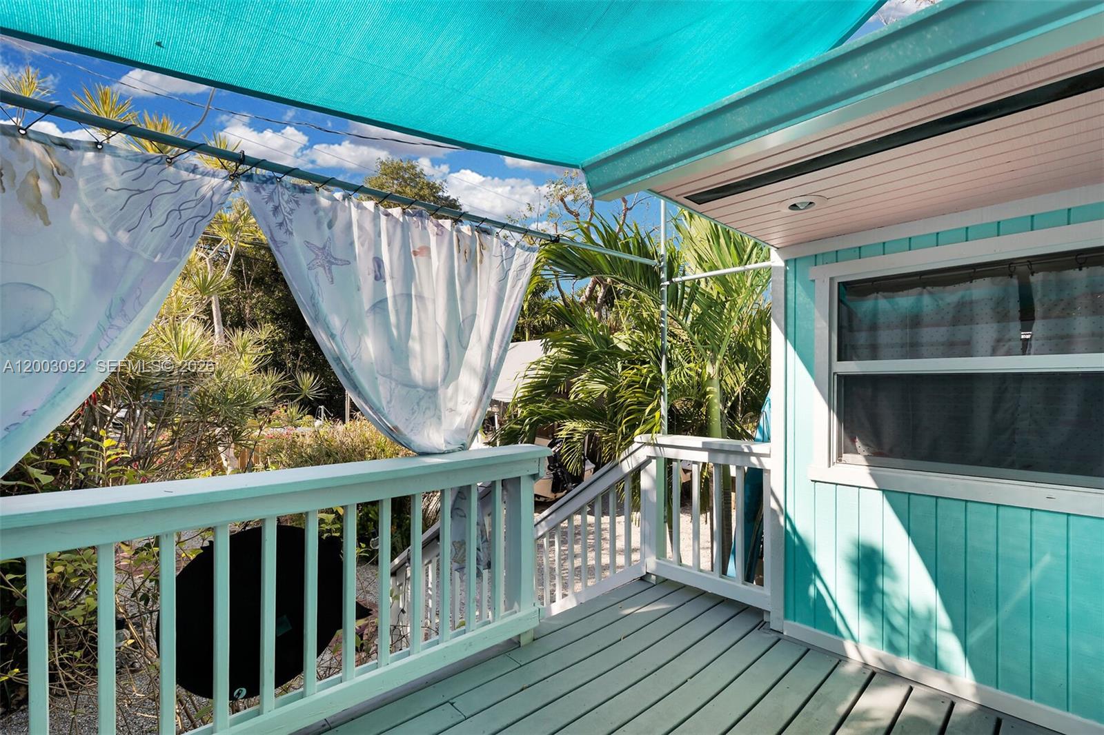 A turquoise-painted wooden deck features a shade canopy, decorative curtains, and white railings — 14 Bonita Ave, Key Largo FL 33037, KEY LARGO, FL