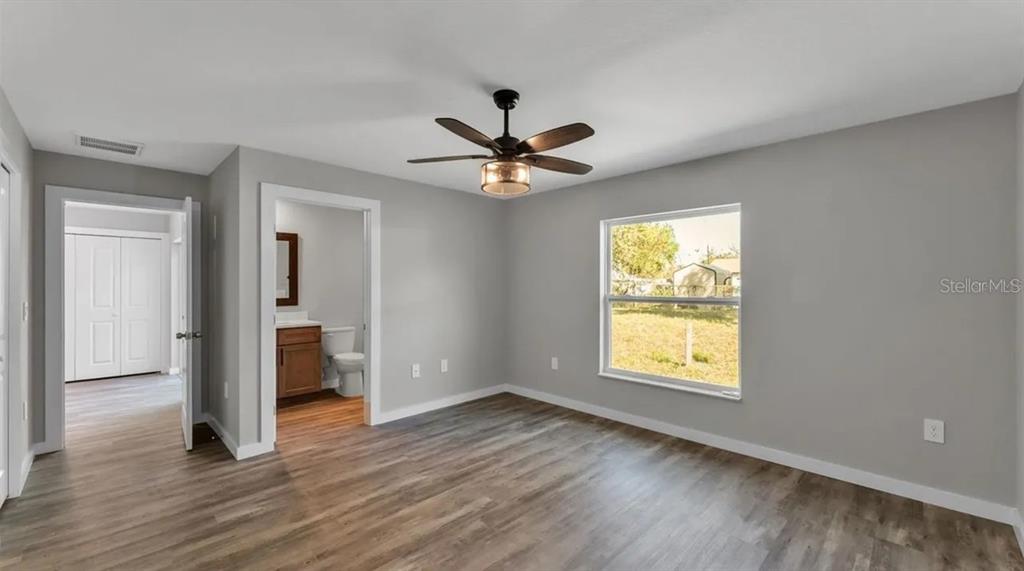 A bedroom with gray walls, wood-look flooring, a ceiling fan, and an attached bathroom — 0 38TH STREET NW, WINTER HAVEN, FL
