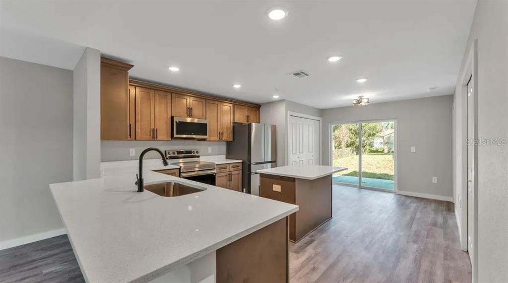 A kitchen features light countertops, wood cabinets, stainless steel appliances, and a central island — 0 38TH STREET NW, WINTER HAVEN, FL