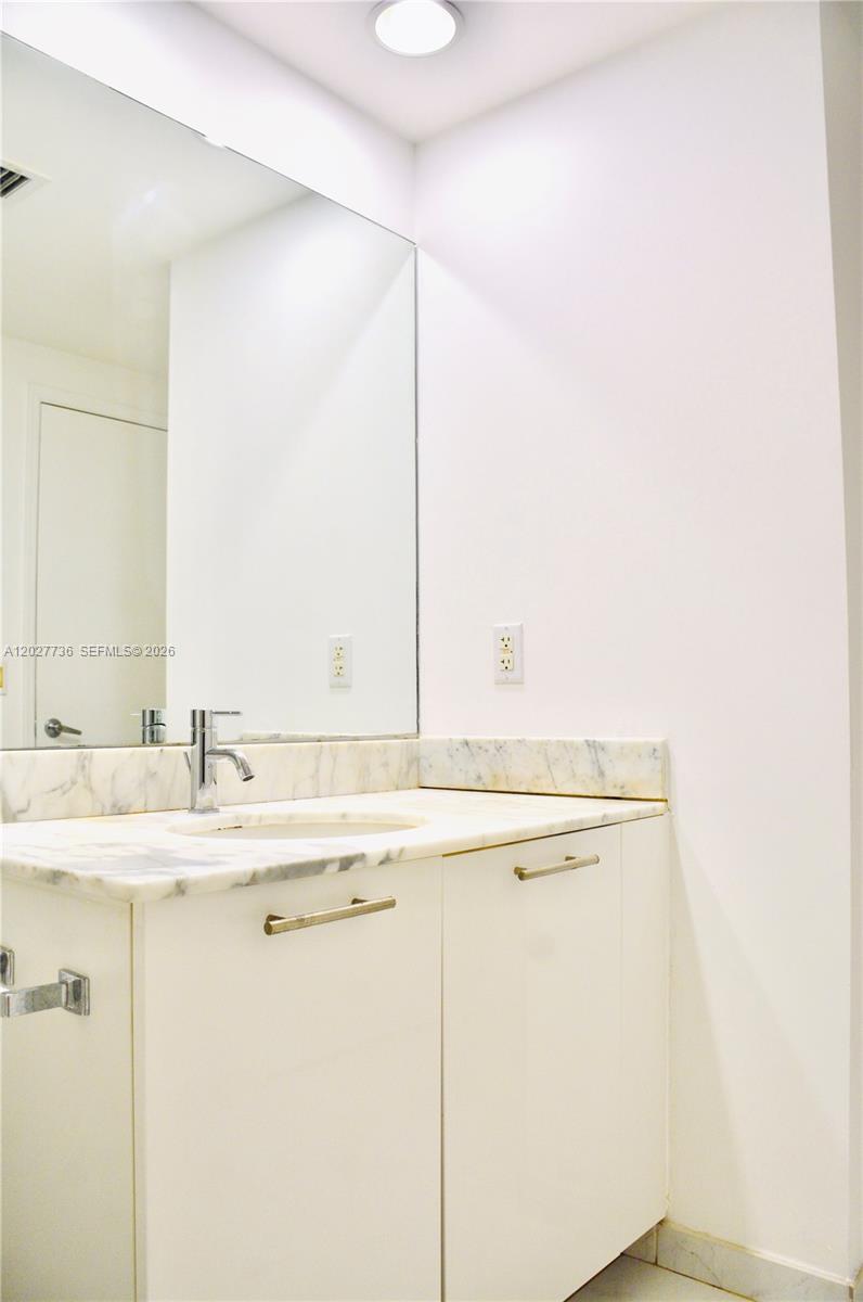 A bathroom features a white vanity with a marble countertop and a large wall mirror — 951 BRICKELL # 2609, Miami FL 33131, MIAMI, FL