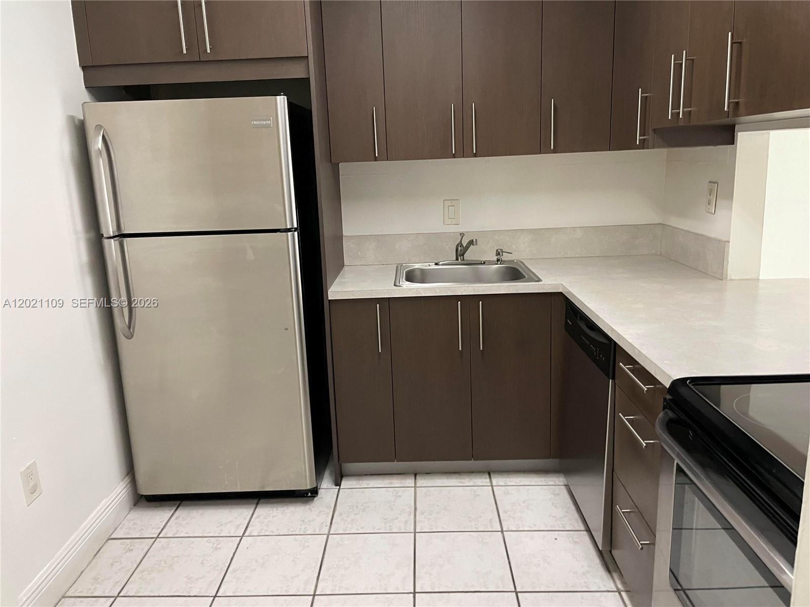 A kitchen features dark wood cabinets, stainless steel appliances, and light-colored countertops — 4920 NW 79th Ave # 212, Doral FL 33166, DORAL, FL
