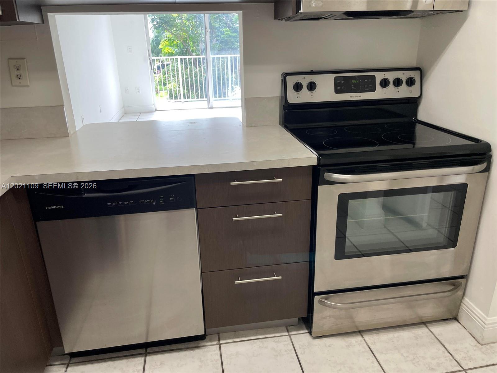 A kitchen features stainless steel appliances, dark wood cabinets, and a pass-through window to a balcony — 4920 NW 79th Ave # 212, Doral FL 33166, DORAL, FL
