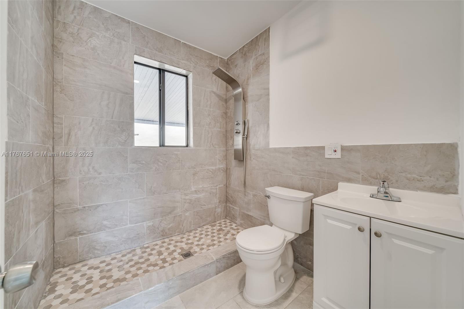 A bathroom features a tiled walk-in shower, a white toilet, and a vanity cabinet — 247 NW 54th St, Miami FL 33127, MIAMI, FL
