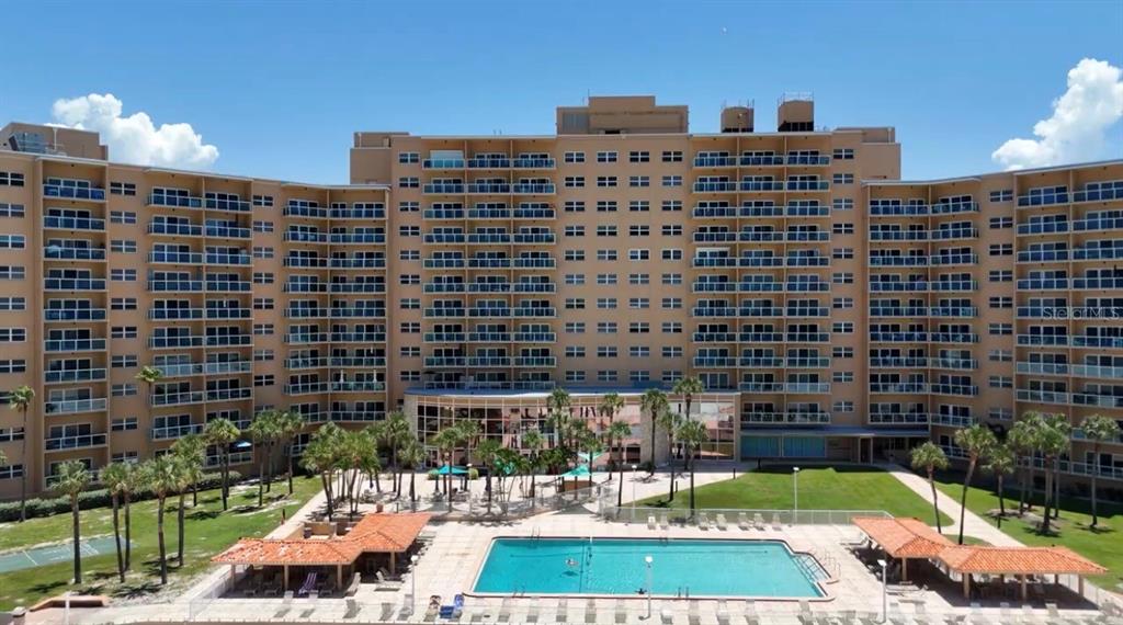 An aerial view of a multi-story tan apartment building with a swimming pool and palm trees — 880 MANDALAY AVENUE UNIT C808, CLEARWATER BEACH, FL