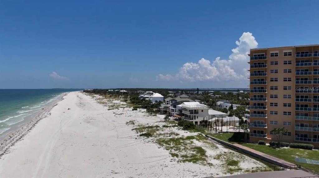 An aerial view of a sandy beach next to a multi-story residential building and houses — 880 MANDALAY AVENUE UNIT C808, CLEARWATER BEACH, FL