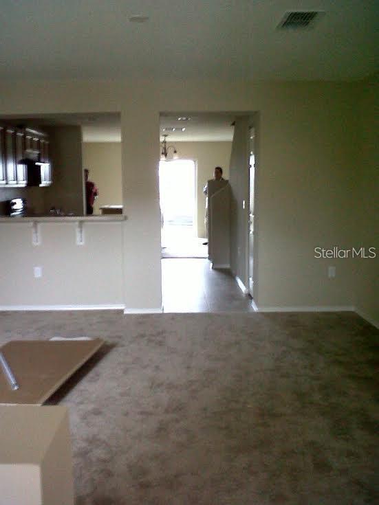 A carpeted room leads to a kitchen pass-through and a doorway opening to an entryway — 3107 SEAVIEW CASTLE DRIVE, KISSIMMEE, FL