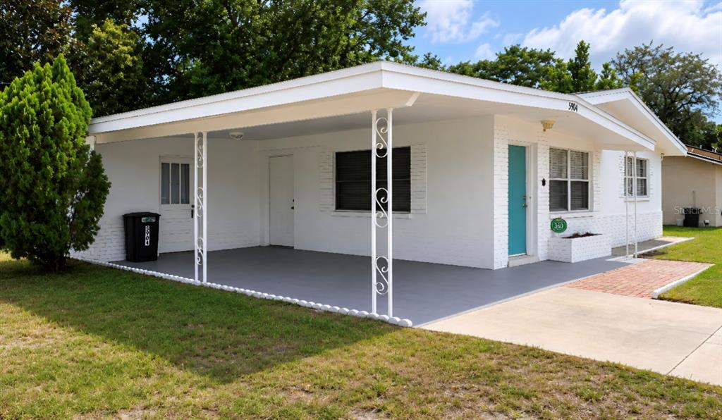 A white house exterior features a large covered carport with decorative metal support columns — 5904 ELM STREET, NEW PORT RICHEY, FL