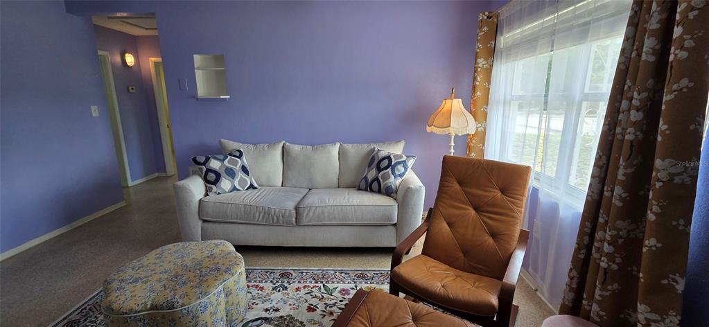 A living room features purple walls, a light-colored sofa, a brown armchair, and patterned curtains — 5904 ELM STREET, NEW PORT RICHEY, FL