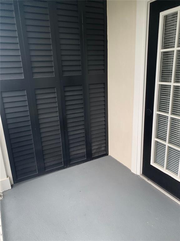 A small gray balcony features black louvered shutters and a glass-paned door — 280 CELEBRATION UNIT 209, CELEBRATION, FL
