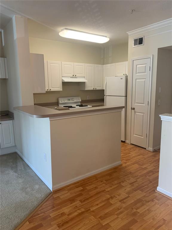 A kitchen features white cabinets, a white stove, a refrigerator, and a breakfast bar — 280 CELEBRATION UNIT 209, CELEBRATION, FL