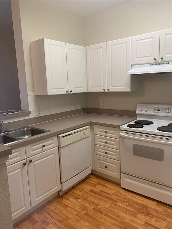 A kitchen features white cabinets, a dishwasher, a stove, and a stainless steel sink — 280 CELEBRATION UNIT 209, CELEBRATION, FL