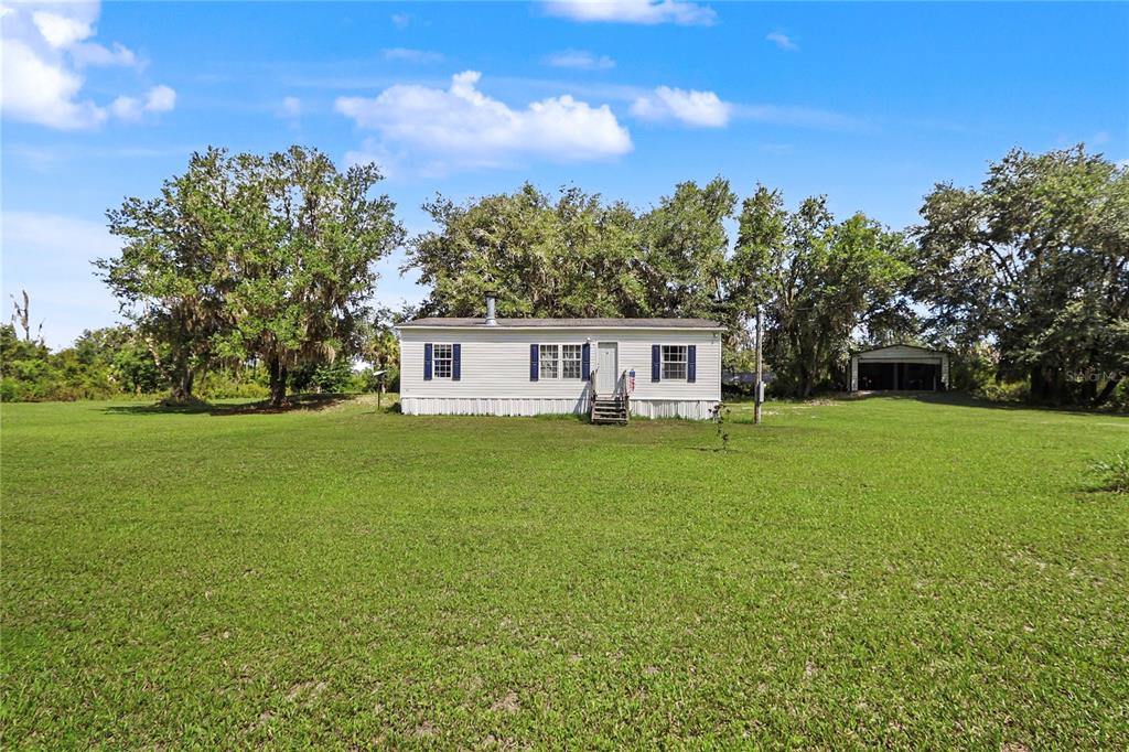 A single-story manufactured home sits in the middle of a large, grassy lot — 5435 NE 153RD PLACE ROAD, CITRA, FL