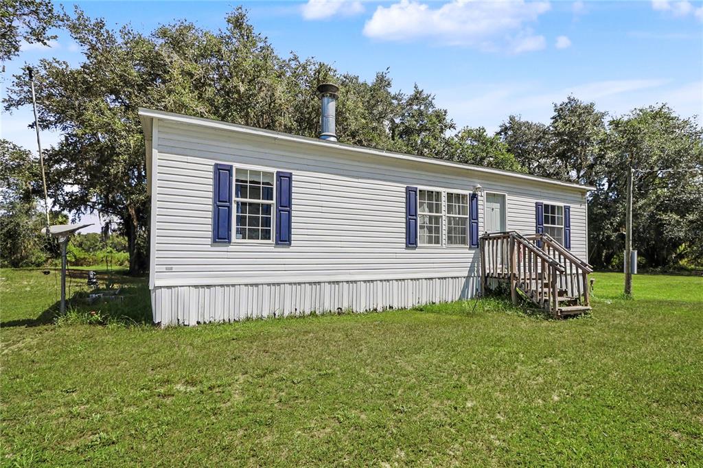 A single-story manufactured home with white siding, blue shutters, and a wooden porch — 5435 NE 153RD PLACE ROAD, CITRA, FL