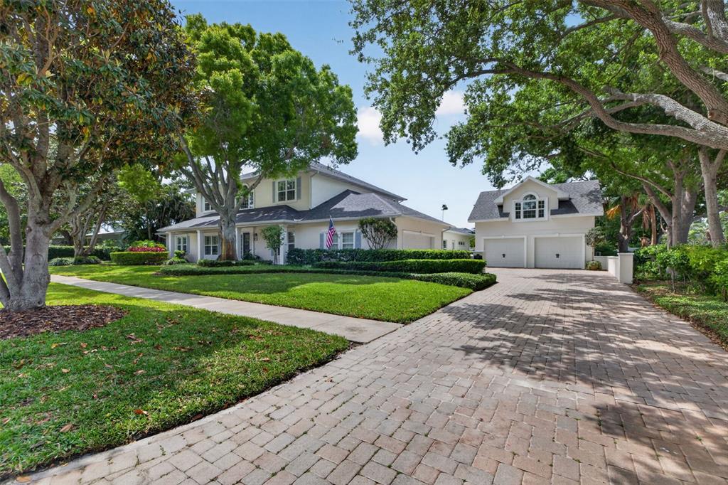 A two-story house with a detached garage and a brick driveway sits on a lawn — 445 PARK AVENUE, BELLEAIR, FL