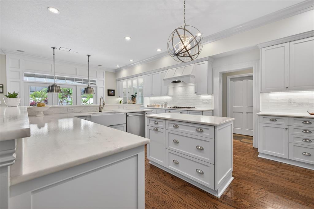 A white kitchen features a marble-topped island, farmhouse sink, and hardwood flooring — 445 PARK AVENUE, BELLEAIR, FL