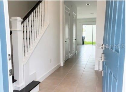 An entryway features a staircase with white railings, tile flooring, and a blue front door — 12632 CLEAR SAPPHIRE DRIVE, WINTER GARDEN, FL