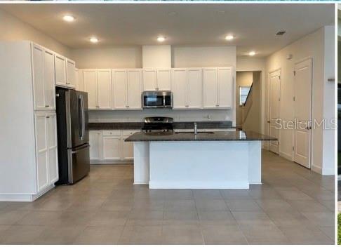 A modern kitchen features white cabinetry, stainless steel appliances, and a central island with countertops — 12632 CLEAR SAPPHIRE DRIVE, WINTER GARDEN, FL